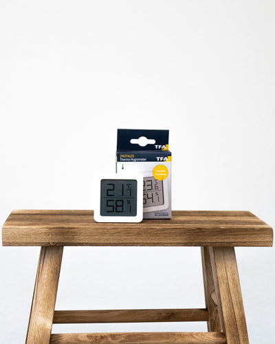 Hygrometer weiss vor seiner Verpackung auf einem Holztisch
