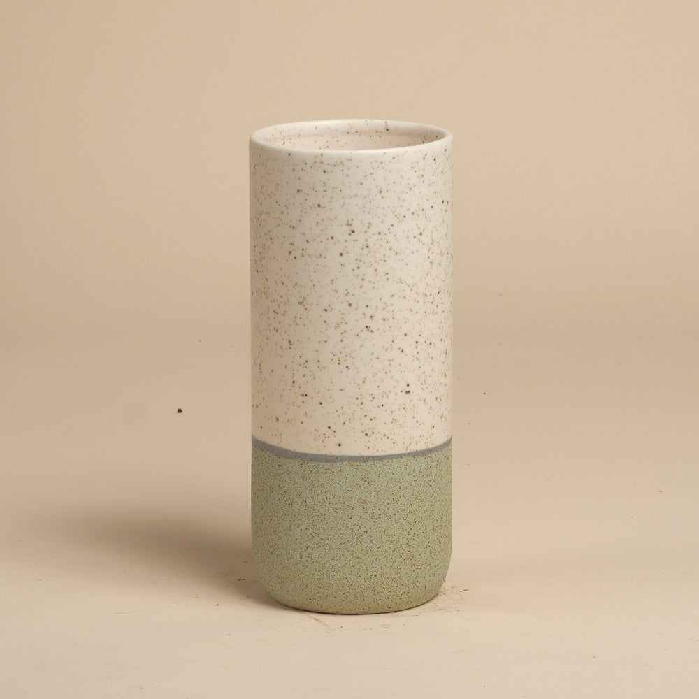 Die feey Keramik-Vase (Variado | 21 cm) ist eine hohe, zylindrische Vase mit einer gesprenkelten, cremefarbenen Oberseite, einer matten, hellgrünen Unterseite und einer dünnen, grauen Trennlinie - ideal für Zimmerpflanzen - auf einem einfarbig beigen Hintergrund.