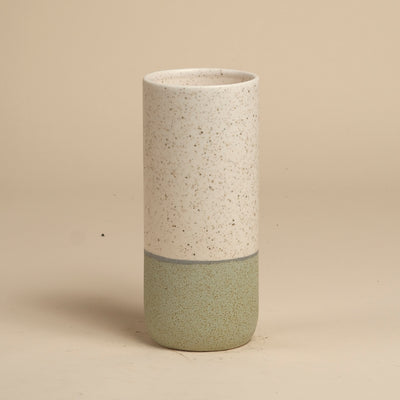 Die feey Keramik-Vase (Variado | 21 cm) ist eine hohe, zylindrische Vase mit einer gesprenkelten, cremefarbenen Oberseite, einer matten, hellgrünen Unterseite und einer dünnen, grauen Trennlinie - ideal für Zimmerpflanzen - auf einem einfarbig beigen Hintergrund.
