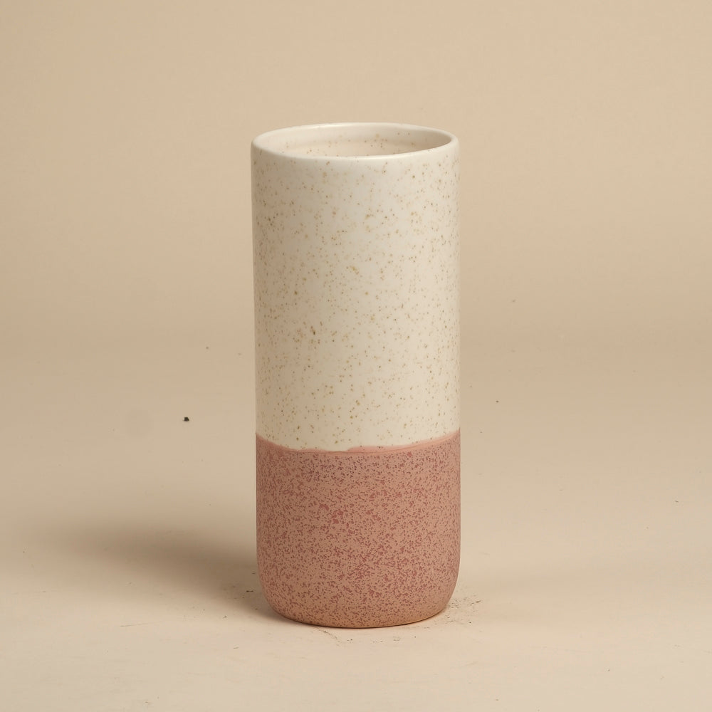 Die feey Keramik-Vase (Variado | 21 cm) ist eine hohe, zylindrische Vase mit einem gesprenkelten, cremefarbenen Oberteil und einem strukturierten, gedämpften, rosafarbenen Unterteil, ideal als Blumenvase für Zimmerpflanzen, abgebildet vor einem schlichten, beigen Hintergrund.