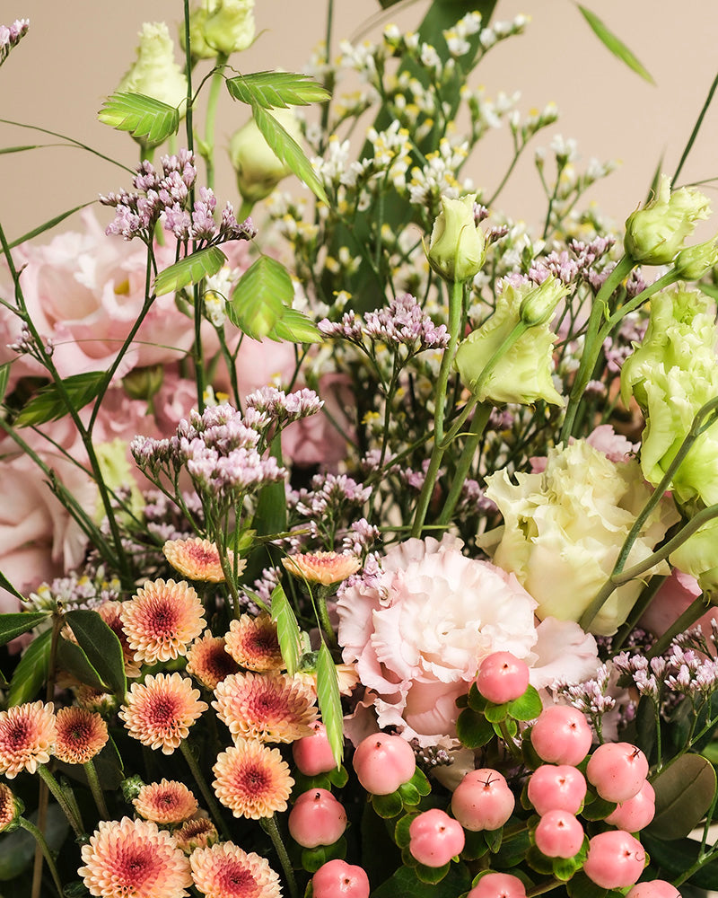 Der Blumenstrauß "Morgenlicht" vereint zartrosa Lisianthus, blassgelbe Blüten, kleine rosa Beeren, violette Statice und pfirsichfarbene Chrysanthemen - handgebunden und voller Herbstzauber für dein Zuhause.