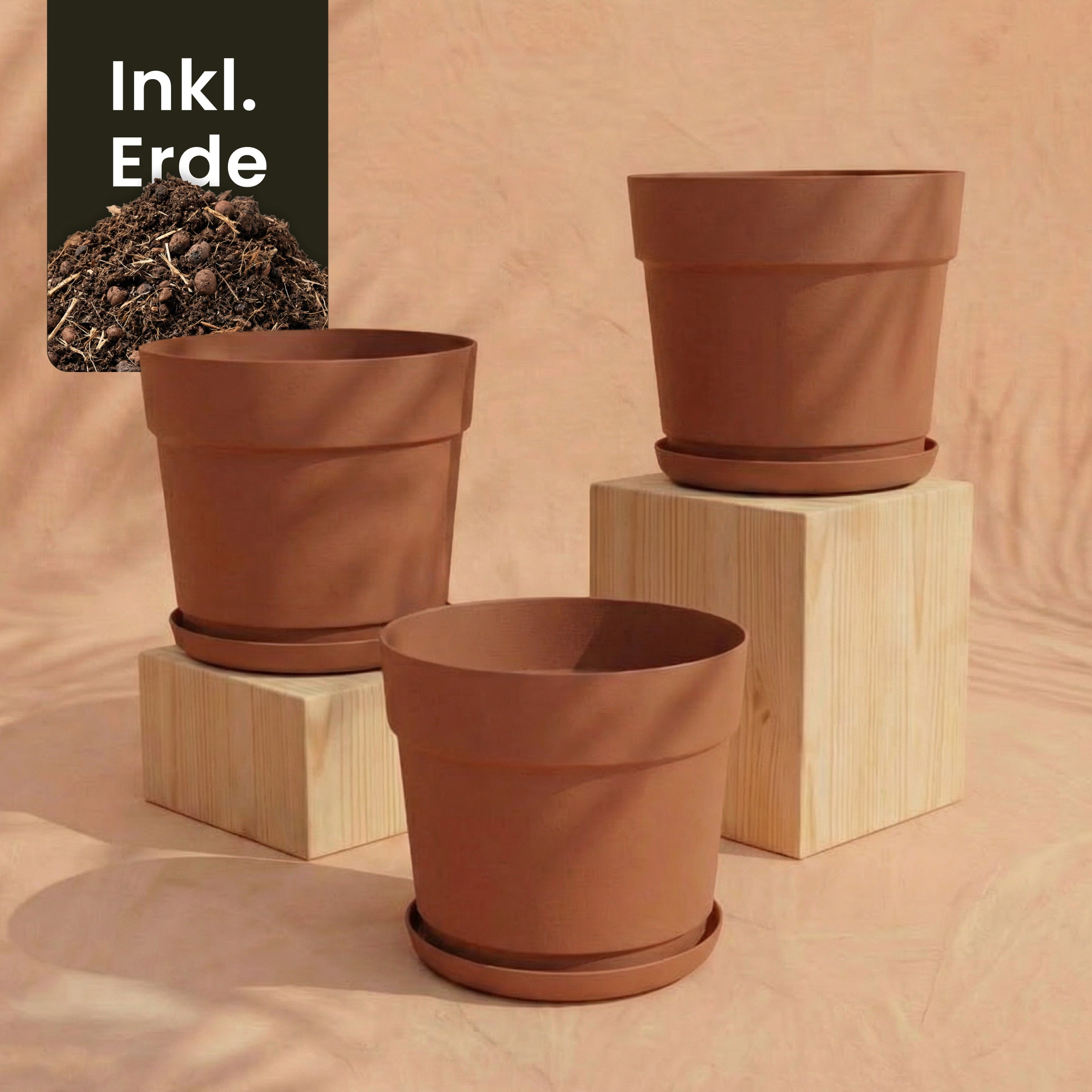 Das Pflanzkübel-Set 'Bloom' (3× 29) aus UV-beständigem, recyceltem Kunststoff mit Untersetzern steht auf hellen Holzblöcken vor pfirsichfarbenem Hintergrund; ein 