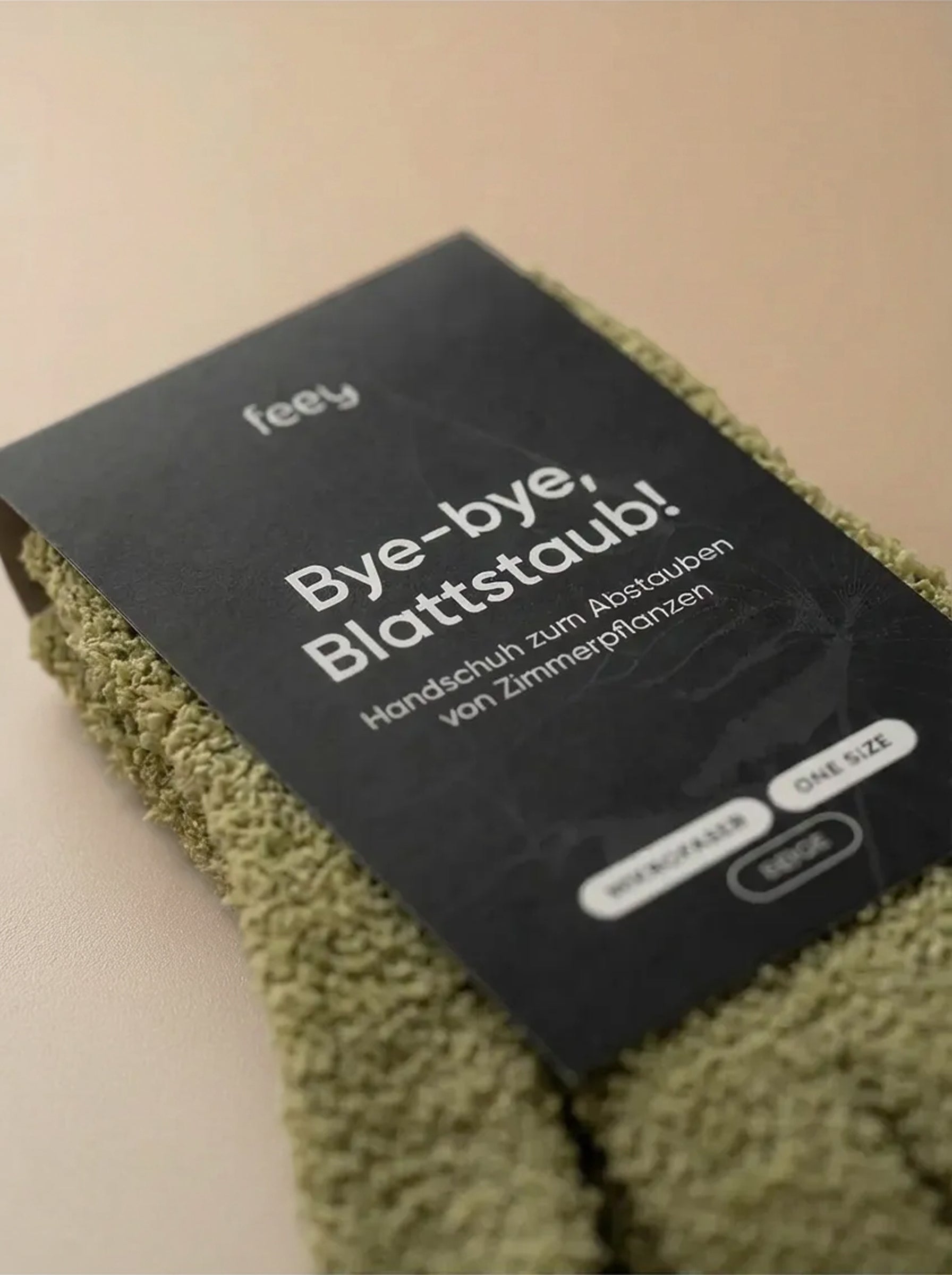 Eine Nahaufnahme von grünen Staubhandschuhen mit einem schwarzen Etikett mit dem Text 