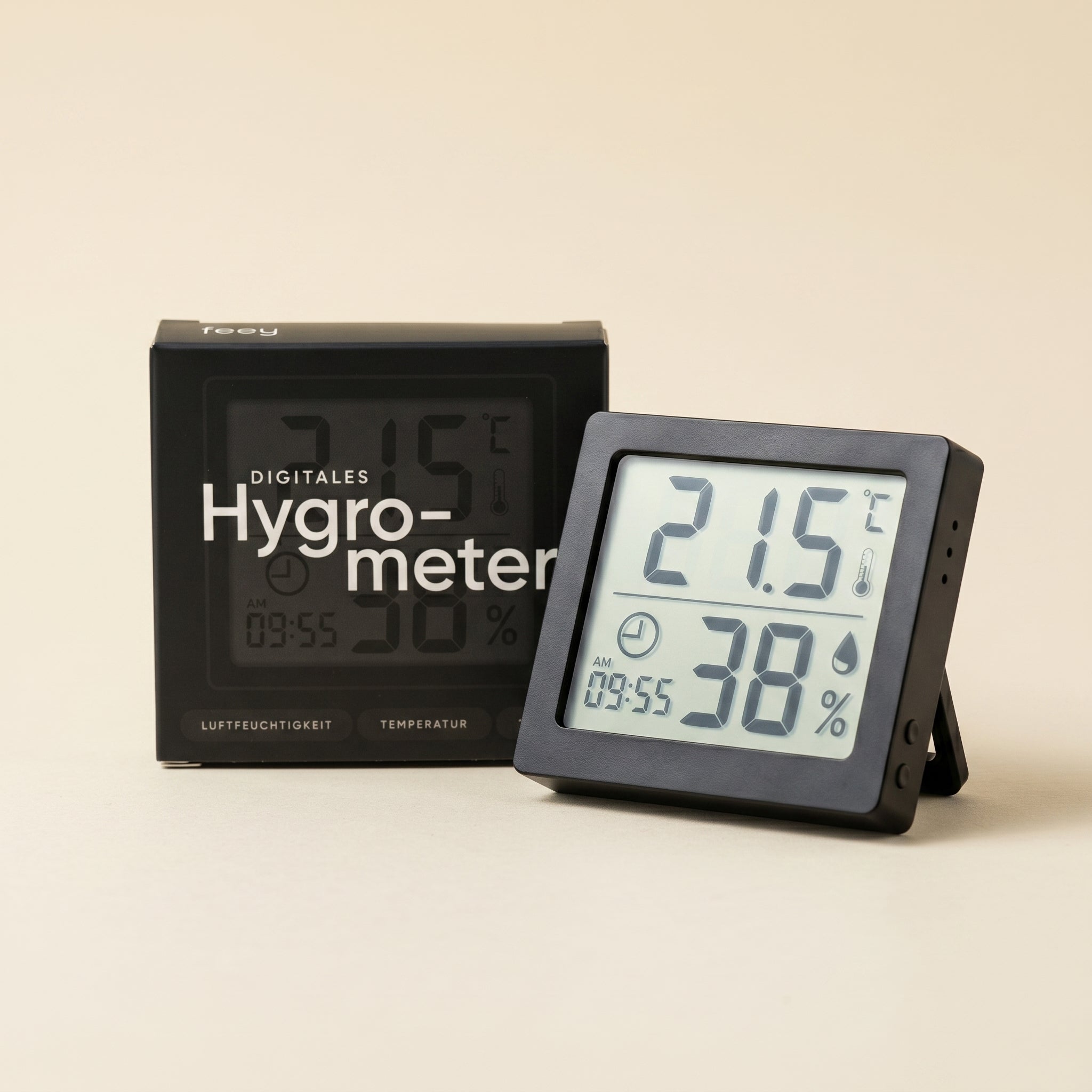 Das schlichte schwarze Hygrometer zeigt 21,5 °C und 38 % Luftfeuchtigkeit an und steht aufrecht neben seiner Schachtel mit der Aufschrift Hygrometer