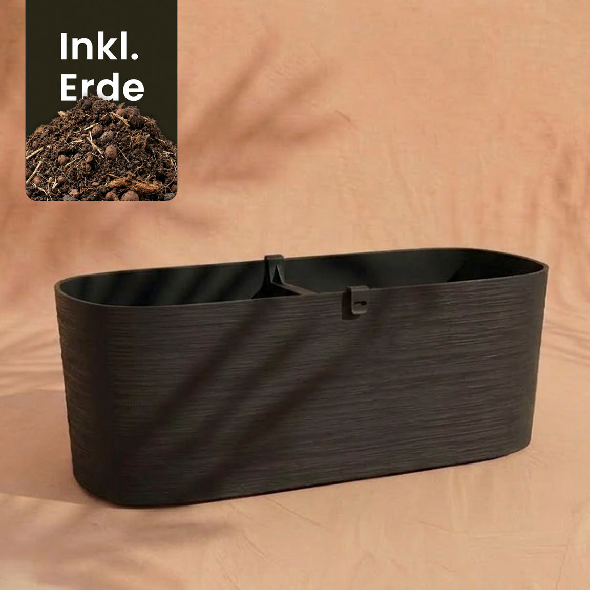 Ein großer, dunkelbrauner rechteckiger Pflanzkasten (Paros | 60 cm) mit Trennwand sitzt auf beigem Stoff. Eine Einlage zeigt Erde mit 