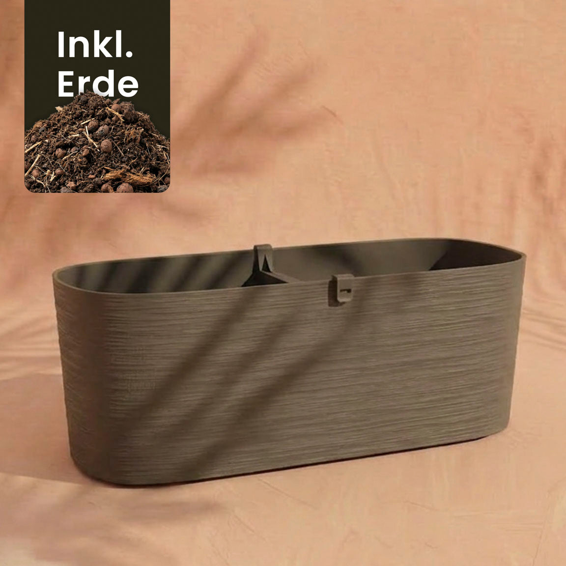 Ein rechteckiger, strukturierter brauner Pflanzkasten (Paros | 60 cm) sitzt auf einer pfirsichfarbenen Oberfläche mit Schatten. Ideal für Balkonpflanzen mit guter Drainage. 