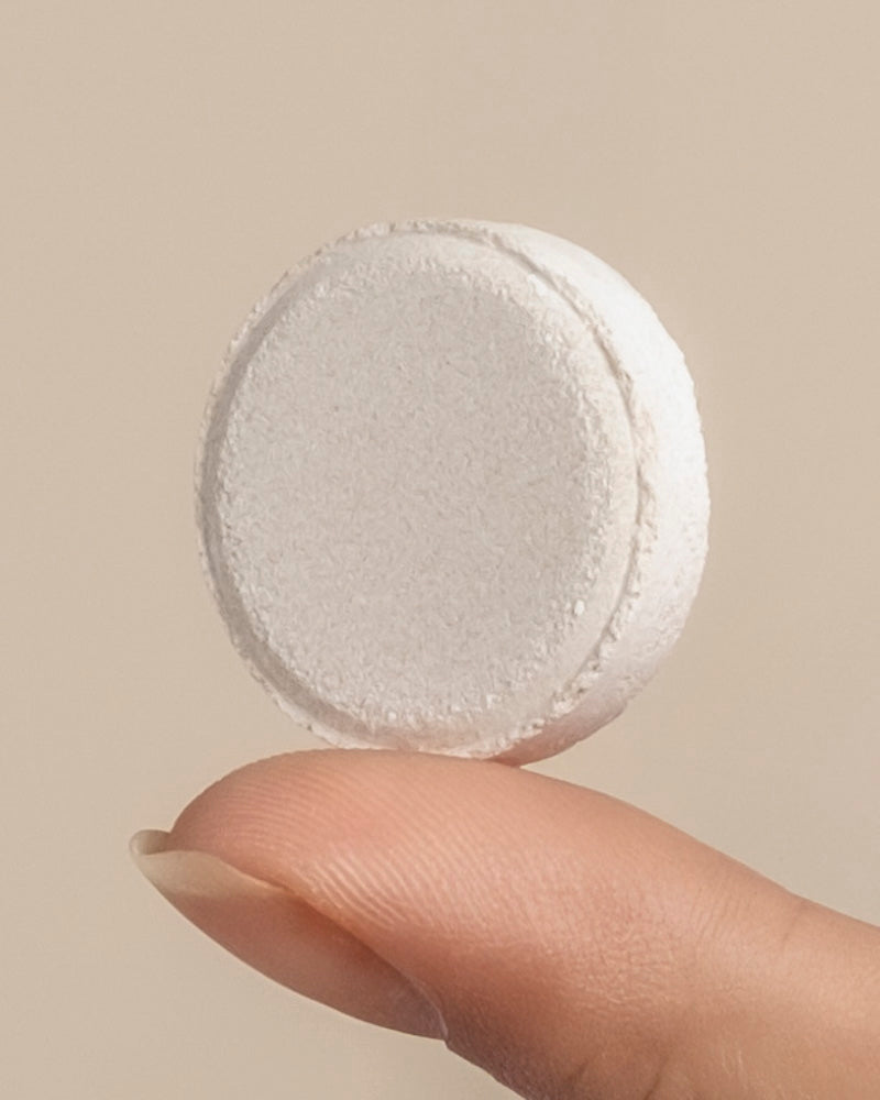 Eine Nahaufnahme einer Hand, die eine große, runde, weiße Mittel gegen kleine schwarze Fliegen-Tablette auf der Spitze des Zeigefingers vor einem hellen Hintergrund hält - perfekt für die biologische Schädlingsbekämpfung, um Trauermücken zu bekämpfen.