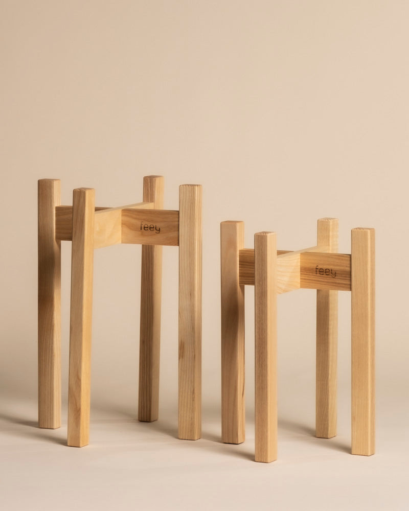 Zwei Pflanzenständer Duo (Stelion | 16, 14) mit minimalistischem Design und feey Gravur stehen in unterschiedlichen Höhen auf beigem Grund - ideal für stilvolle Zimmerpflanzen.