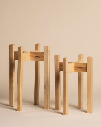 Zwei Pflanzenständer Duo (Stelion | 16, 14) mit minimalistischem Design und feey Gravur stehen in unterschiedlichen Höhen auf beigem Grund - ideal für stilvolle Zimmerpflanzen.