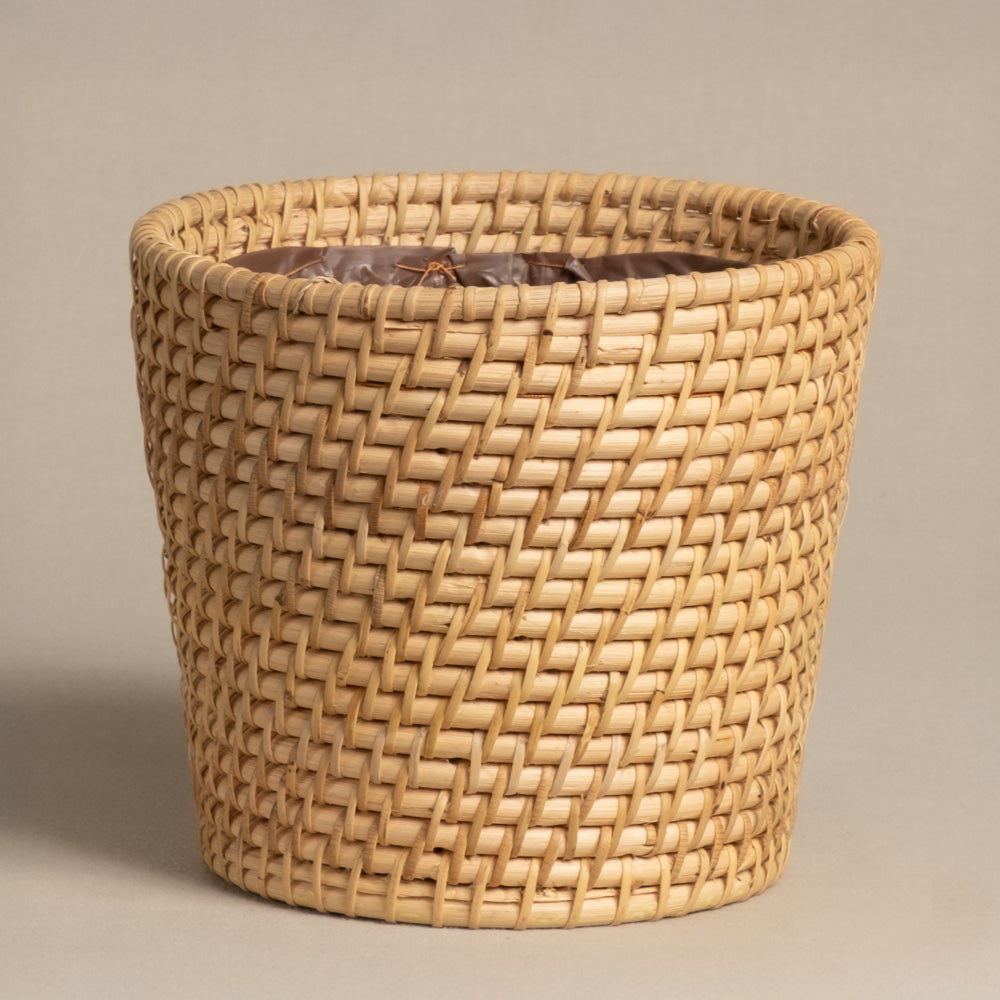 Der Pflanzenkorb aus Rattan (Calen | 18 cm Ø) ist ein runder, hellbrauner handgewebter Korb mit enger diagonaler Flechtung auf schlichtem, neutralem Hintergrund.