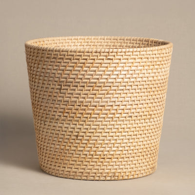 Der Pflanzenkorb aus Rattan (Calen | 25cm Ø) ist ein handgefertigter, runder Korb mit heller Farbe, weitem Öffnungsrand und schlichtem, eng geflochtenem Muster – abgebildet vor beigem Hintergrund.