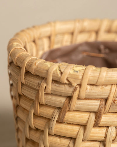 Nahaufnahme des Rattan-Babypflanzen-Korbs 'Calen' (3 Stk.): handgefertigter Weidenkorb mit hellbrauner, natürlicher Textur. Der obere Rand ist durch das detaillierte Rattan-Geflecht und den sichtbaren Kunststoffeinsatz im Inneren hervorgehoben.