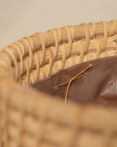 Nahaufnahme des Randes des Pflanzenkorbs aus Rattan (Calen | 22 cm Ø). Er zeigt helle, verflochtene Fasern und ein braunes Leder- oder Kunstlederfutter mit hellbraunen Nähten. Der perfekte Dekokorb für Ihr Zuhause.