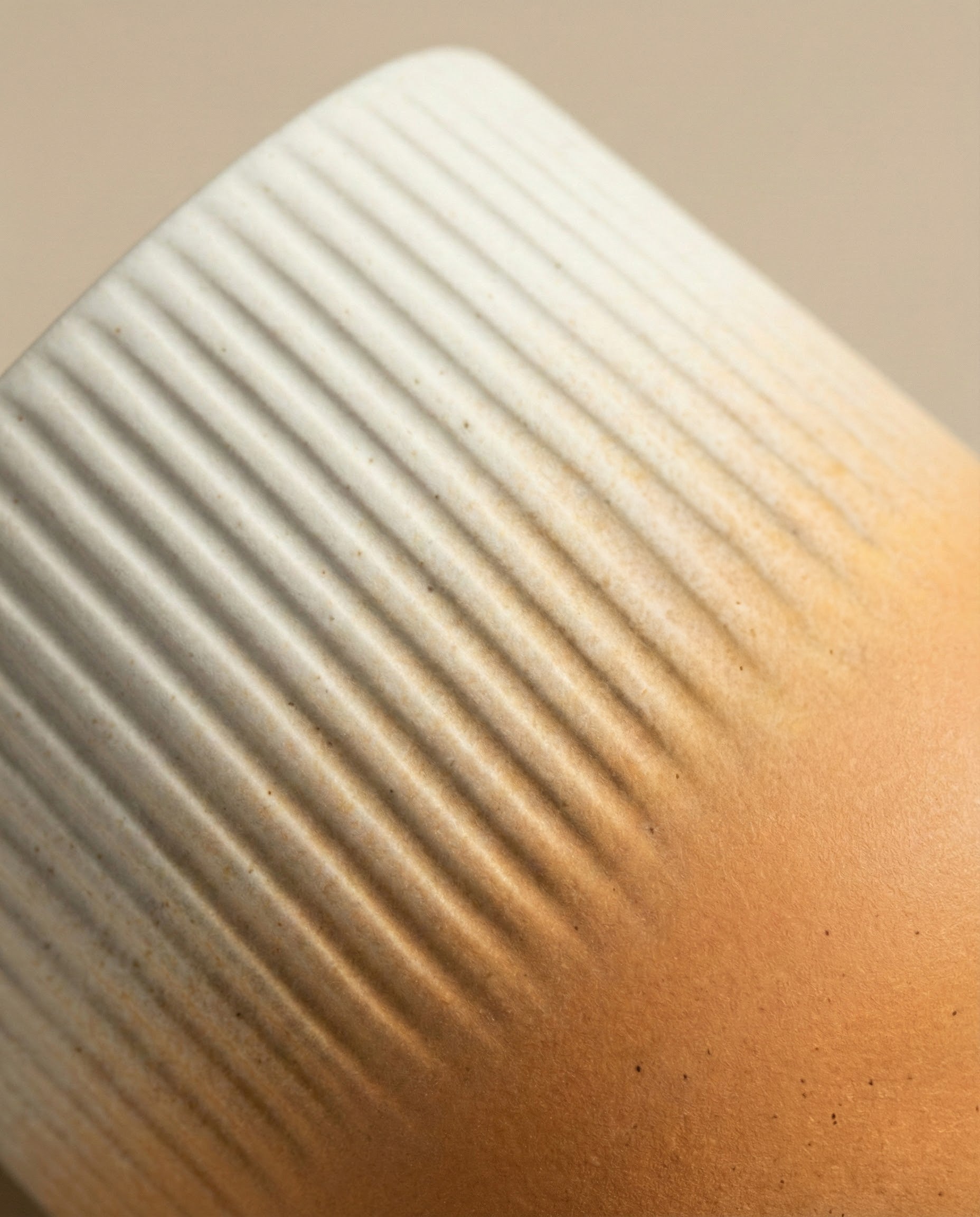 Nahaufnahme des feey Keramik-Topfes (Rilio | 14 cm ø): Keramik-Pflanzgefäß mit gerippter oberer Hälfte, glatter matter unterer Hälfte und sanftem Farbverlauf von hellbeige zu warmem braun - perfekt für Ihre Lieblings-Zimmerpflanze.