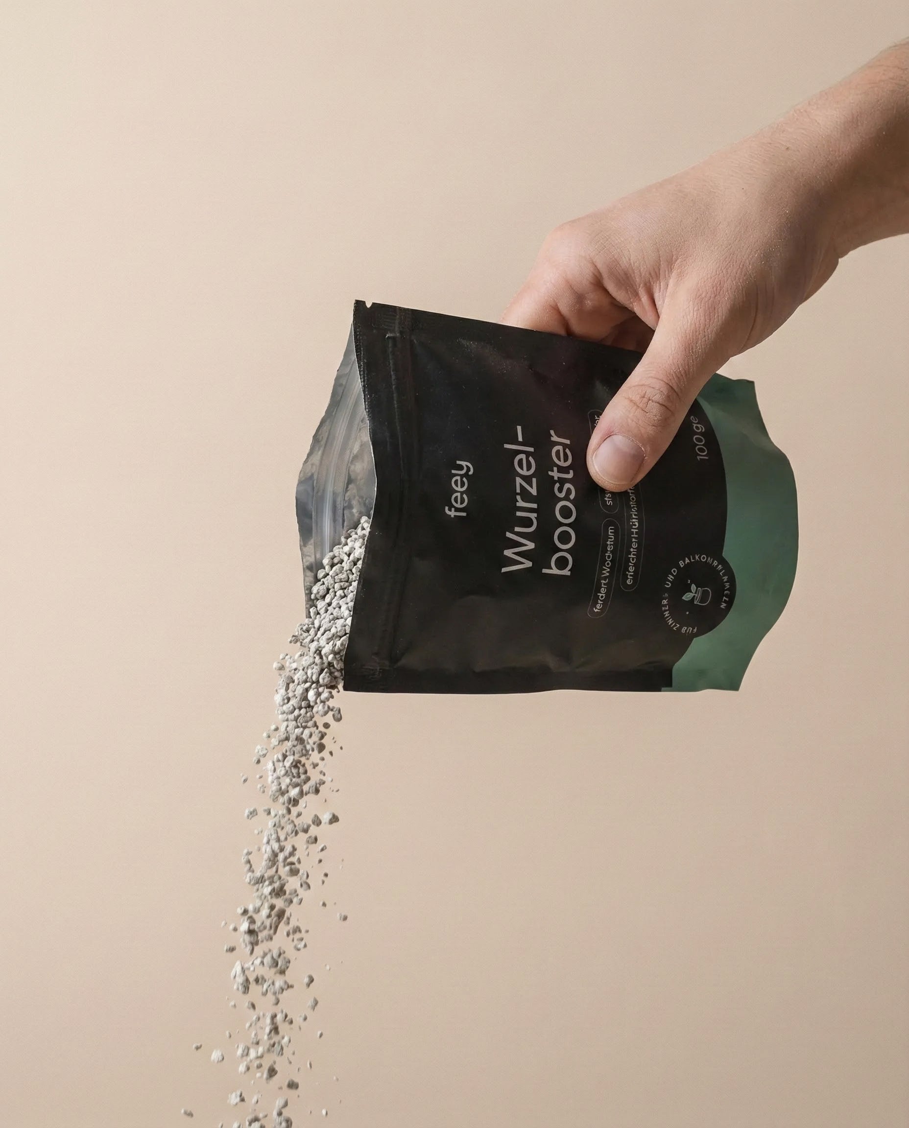 Eine Hand schüttet kleine weiße Körnchen aus einem schwarz-grünen Beutel mit der Aufschrift 