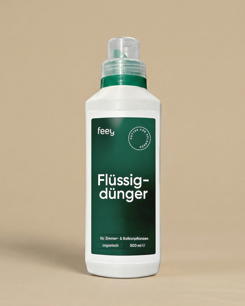 Auf neutralem Hintergrund steht eine weiße Flasche mit grünem Etikett und Deckel mit der Aufschrift "Flüssigdünger", ein organischer Flüssigdünger für Zimmer- und Balkonpflanzen, 500 ml.