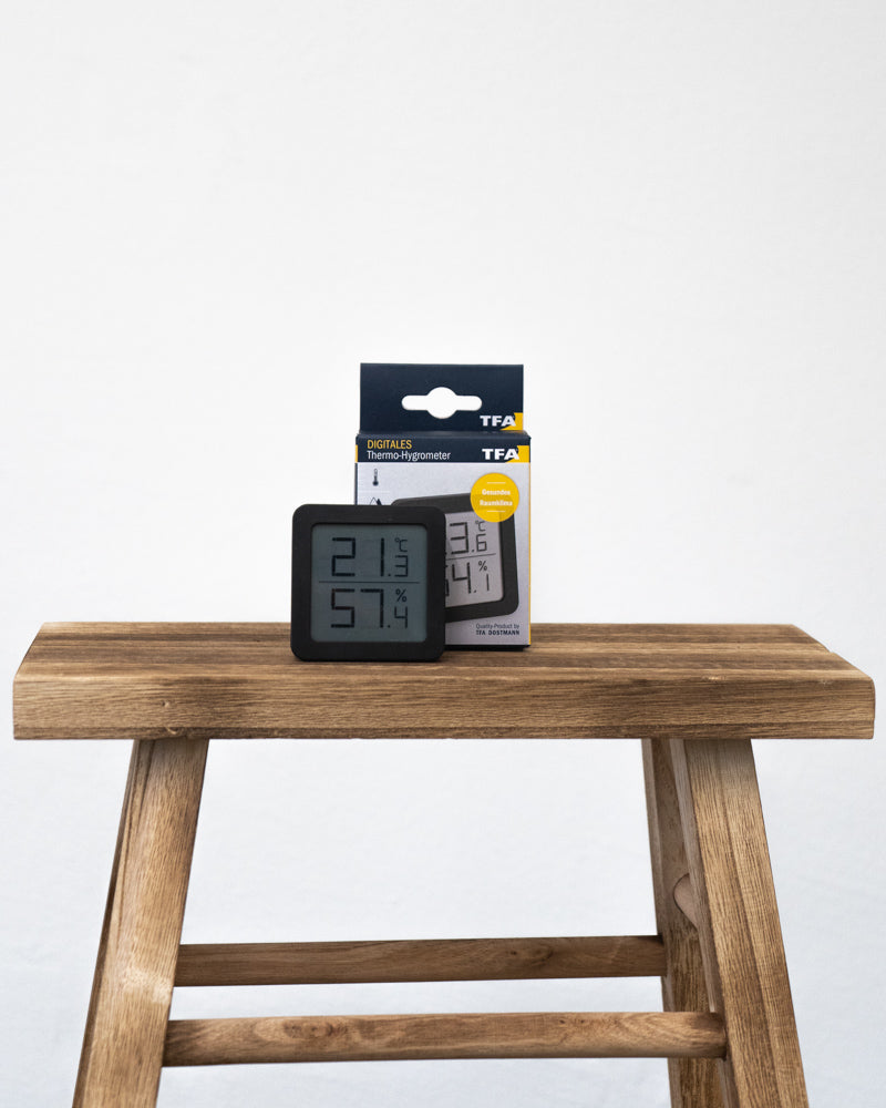 Hygrometer schwarz vor seiner Verpackung auf einem Holztisch