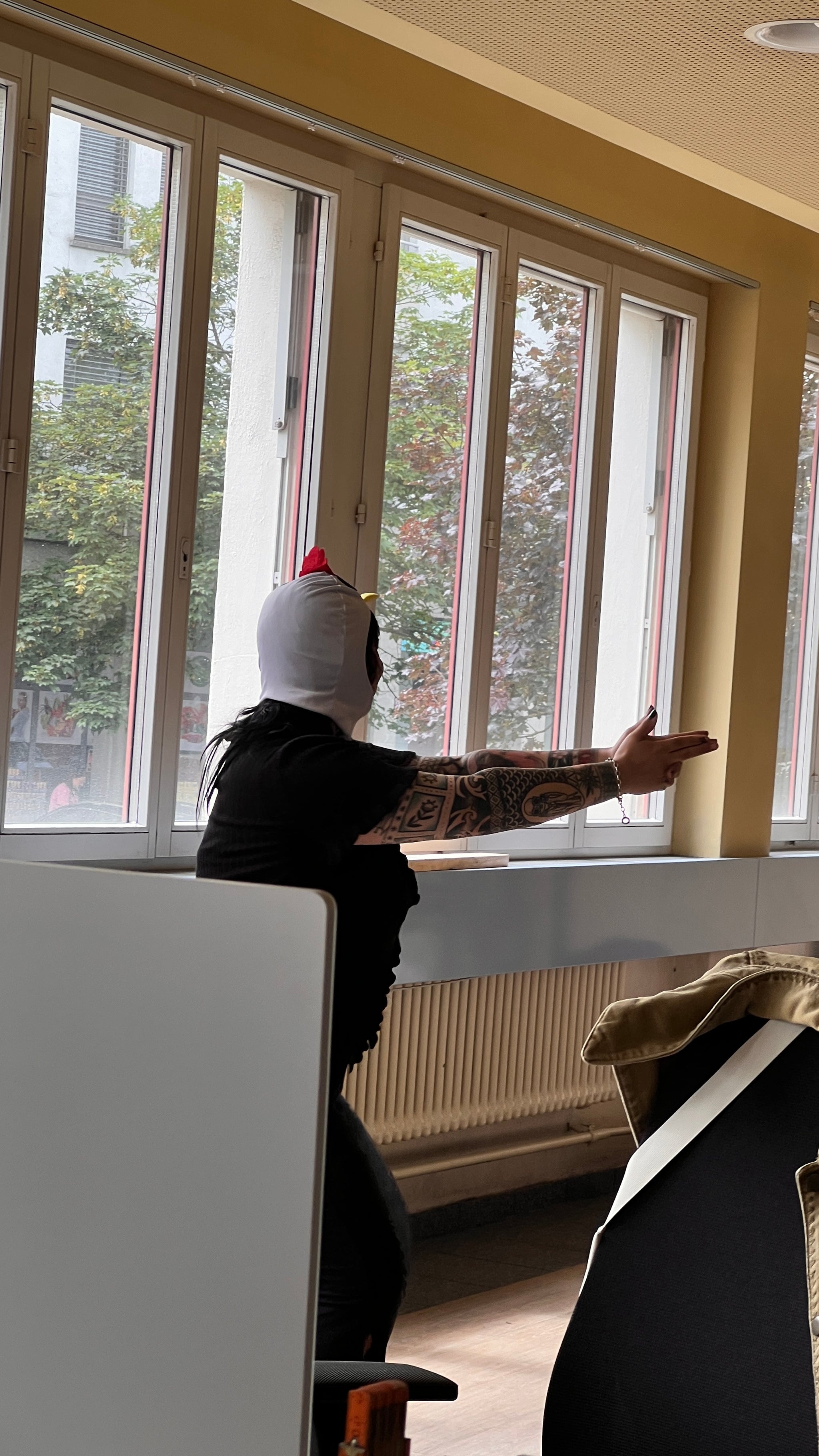 Person, die mit einer Hühnermaske verkleidet eine Pistolen-Geste macht.