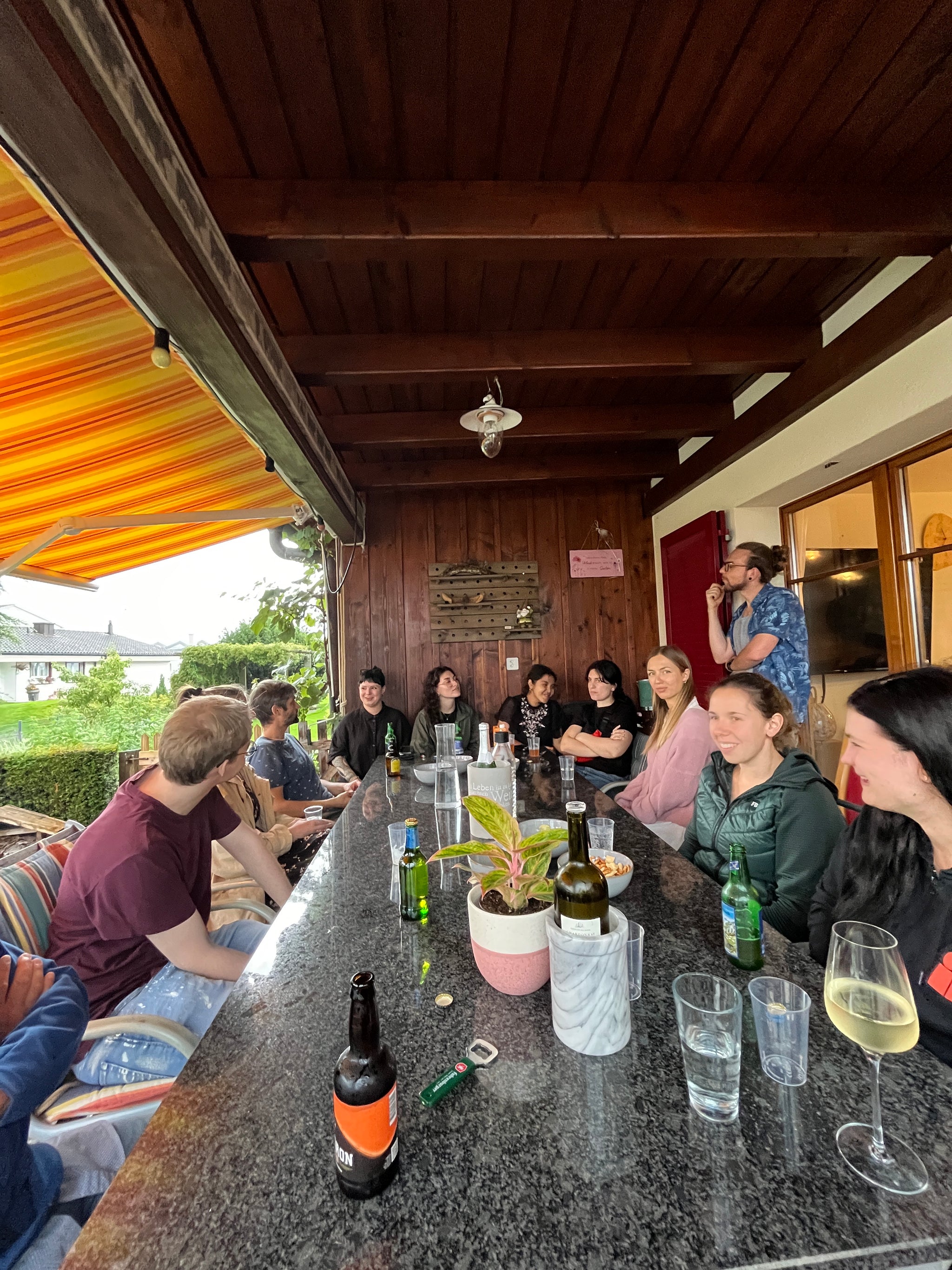 Viele Leute sitzen um einen Steintisch und geniessen einen entspannten Abend.