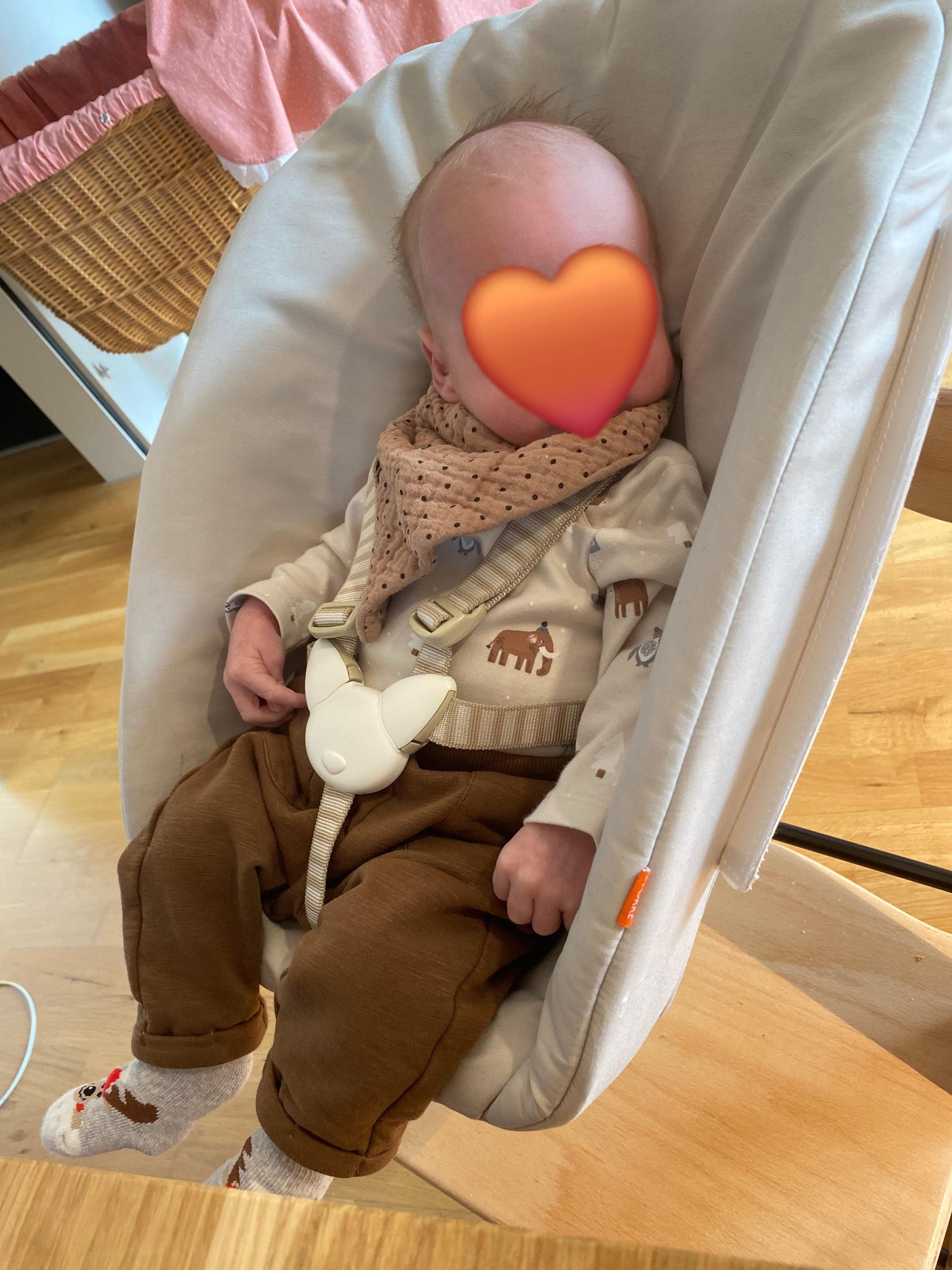 Baby liegt mit brauner Kleidung in einem Sessel