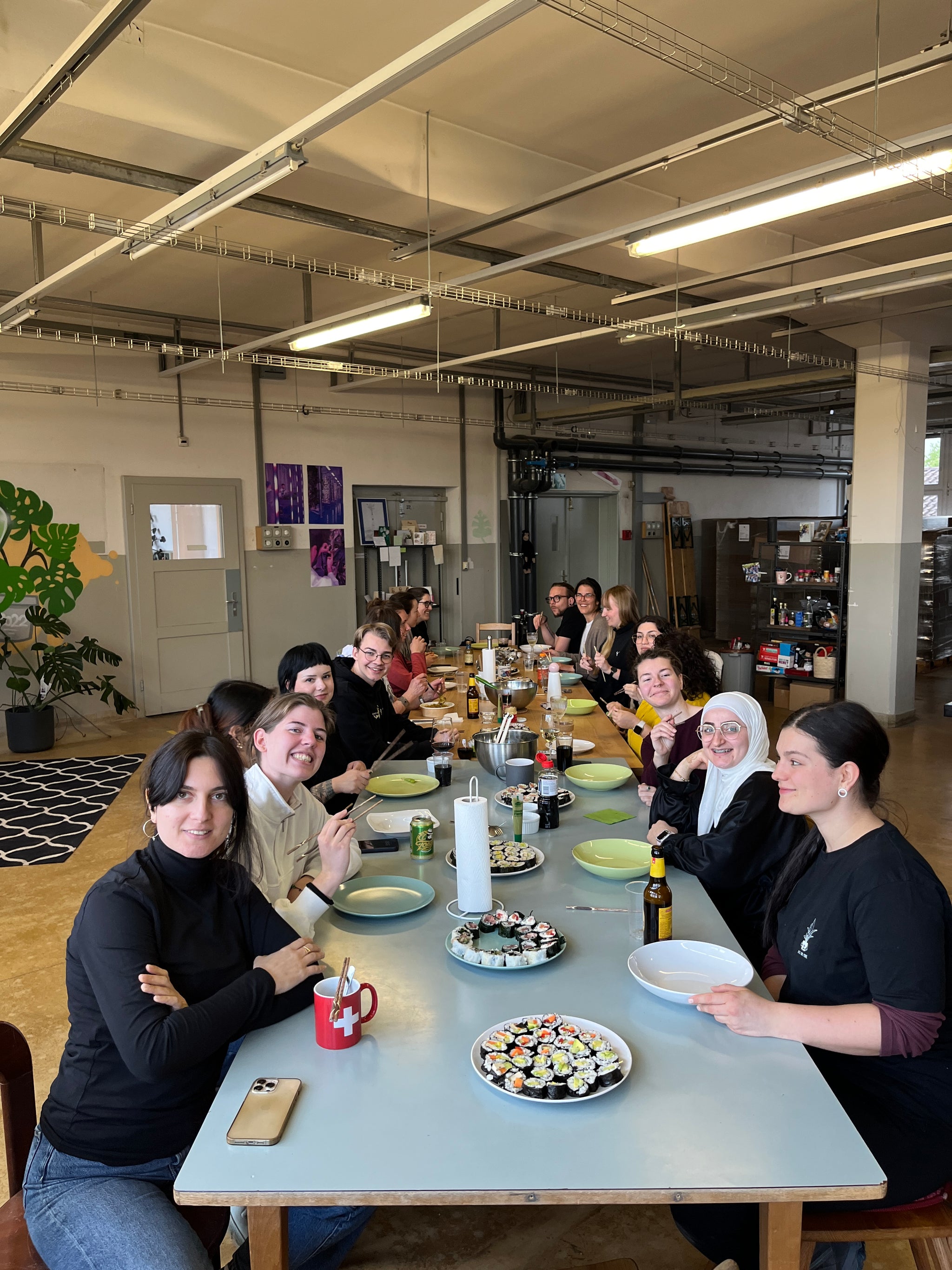 16 Personen an einem langen Tisch mit selbstgemachtem Sushi.