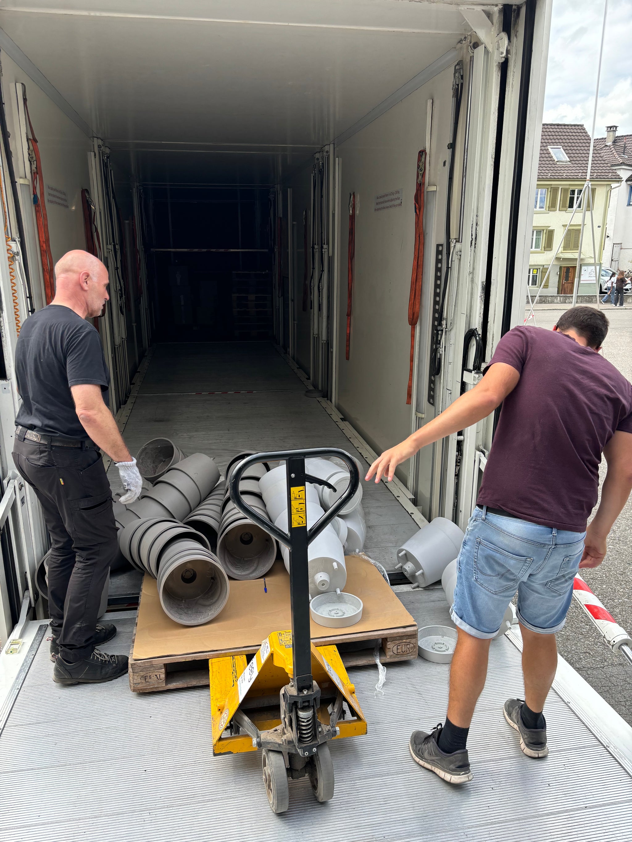 Zwei Personen hinter einem leeren Lastwagen mit einer Palette mit umgestürzten Pflanzkübel.