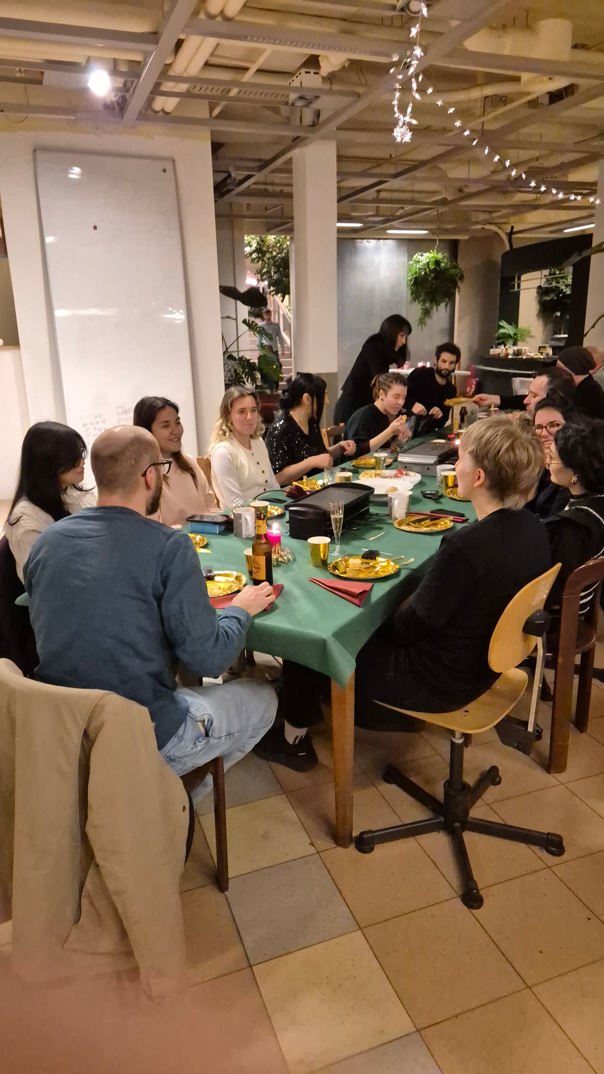 Grosser, langer Esstisch mit vielen Leuten beim Raclette-Essen.