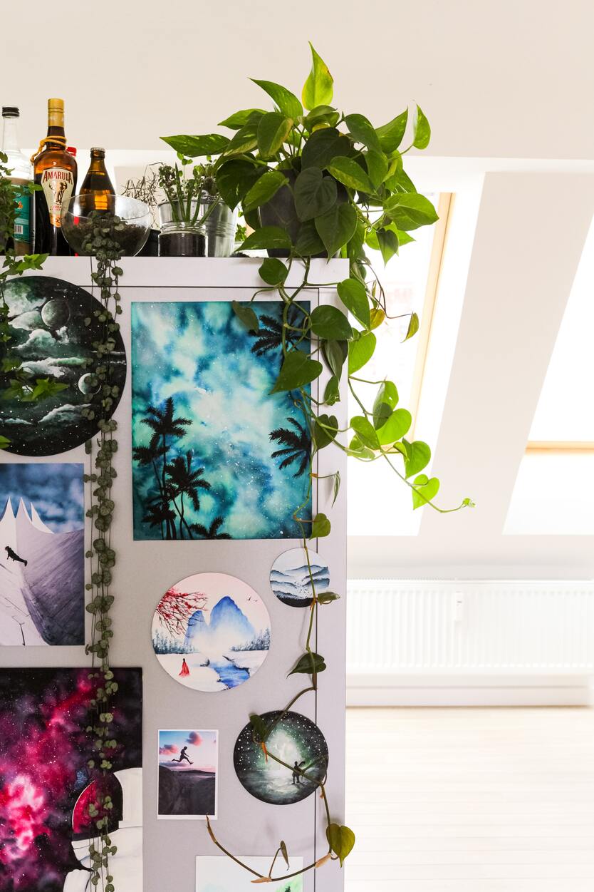 Weisser Küchenschrank mit vielen Postkarten, obenauf diverse Hängepflanzen