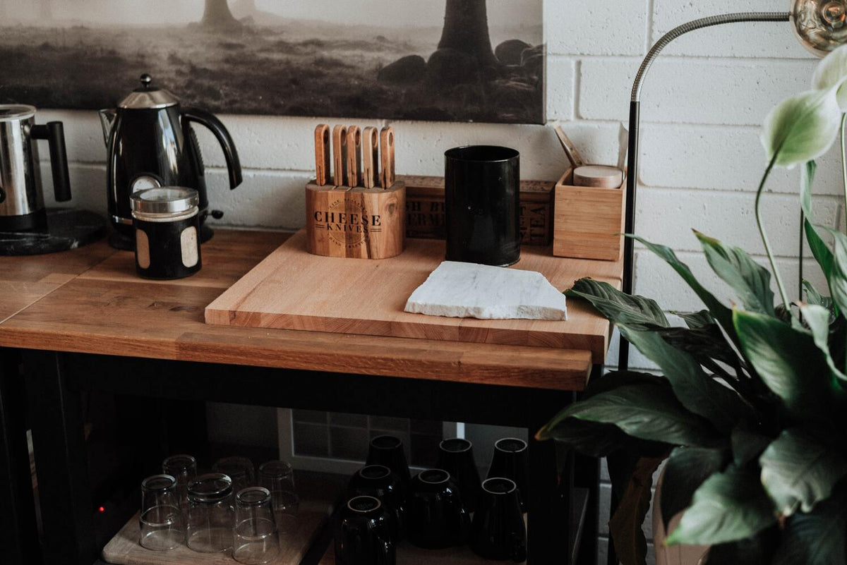 Schlichte Küche mit einem Holztisch und Holzutensilien, daneben ein grosses Einblatt