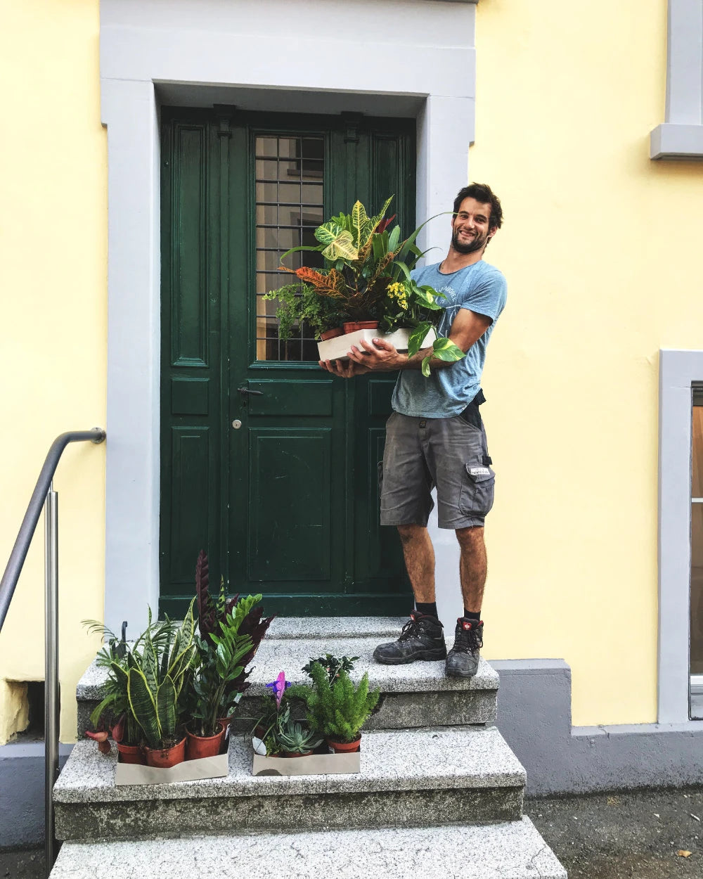 Janko mit Pflanzen auf einer Treppe vor einer Haustüre